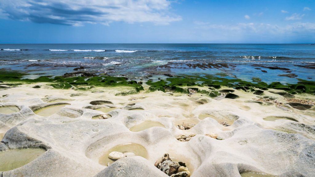 Plage de Balangan Beach à Bali, avec son sable blanc et ses algues vertes à marée basse