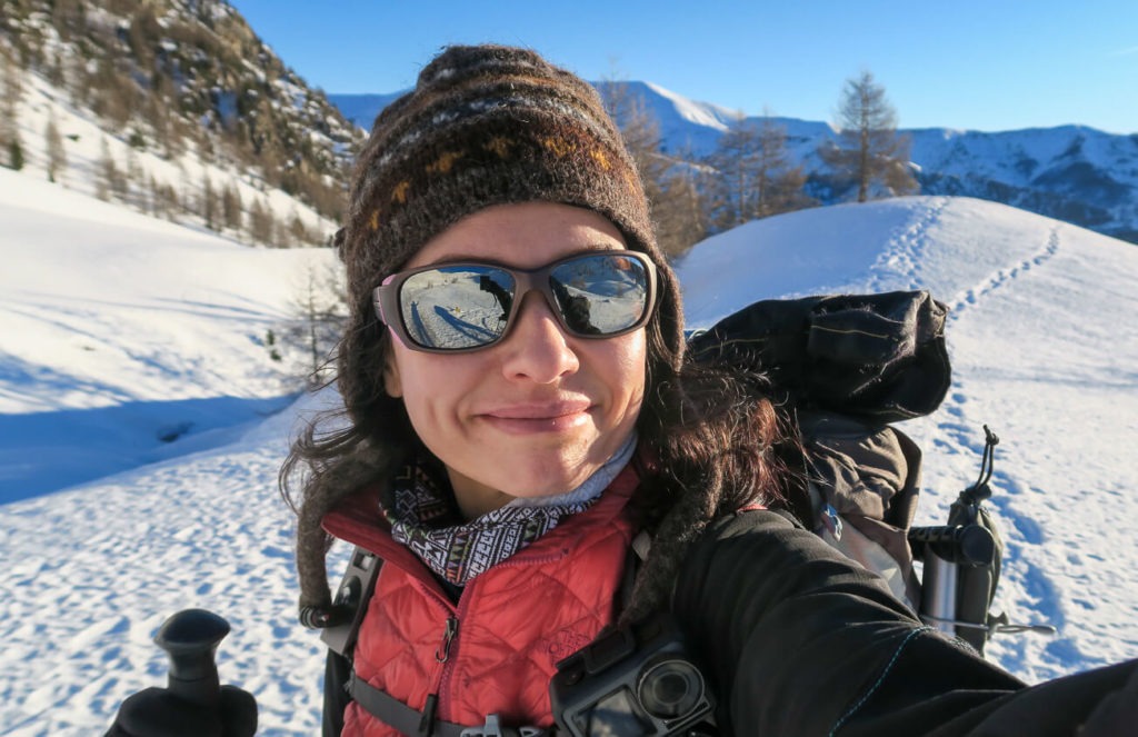 Aude avec lunettes de soleil et bonnet sur fond de montagnes enneigées