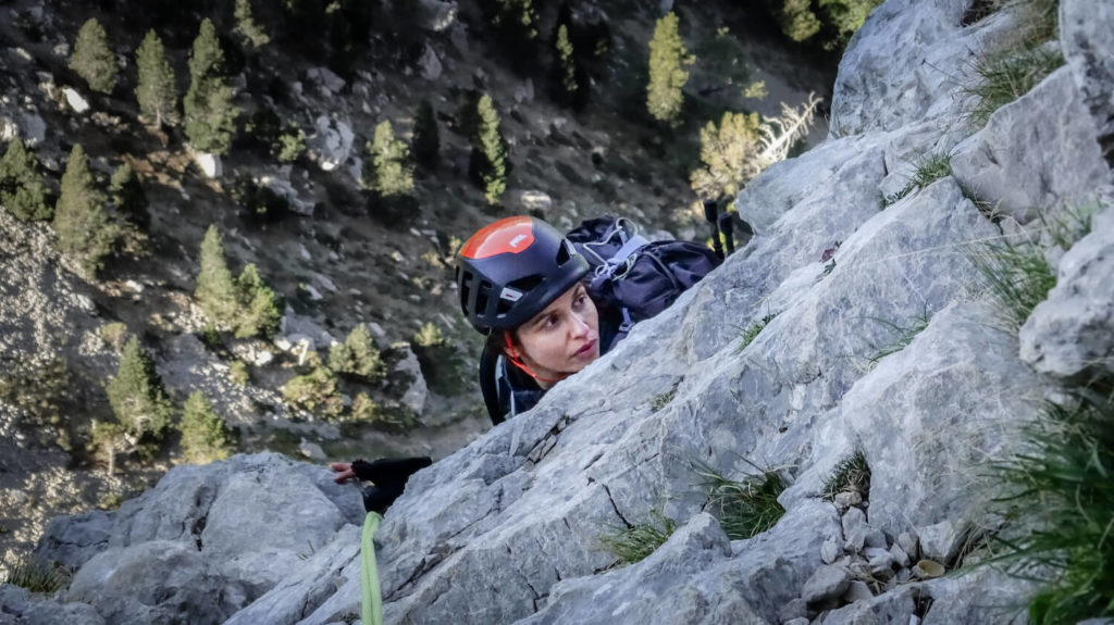 Femme avec casque d'escalade sous une pente de rocher