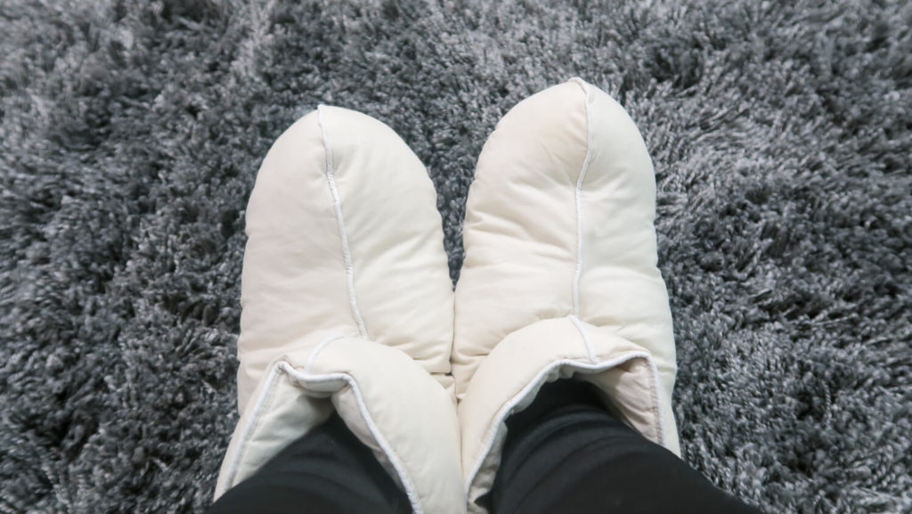chaussons-en-duvet-sur-tapis-moelleux-gris