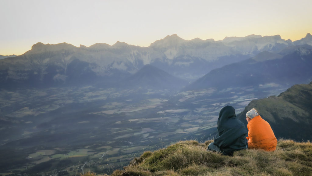 Jeunes filles avec couvertures qui assistent au lever de soleil sur le sommet du Mont Aiguille