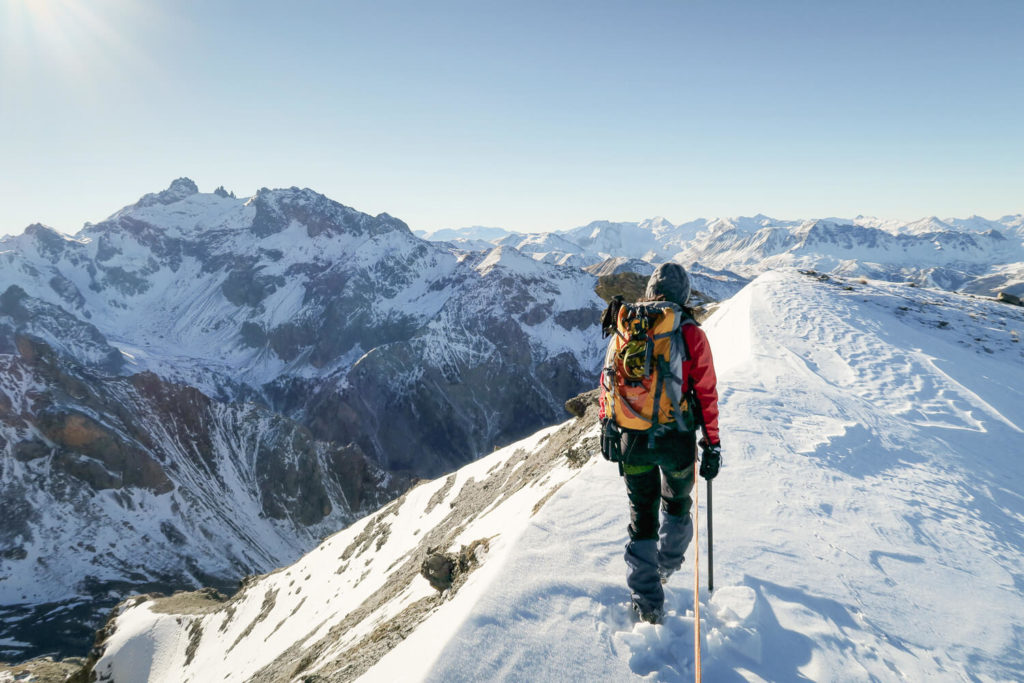 Femme marchant de dos sur la crête de la Main de Dieu dans une course d'alpinisme, dans le Queyras