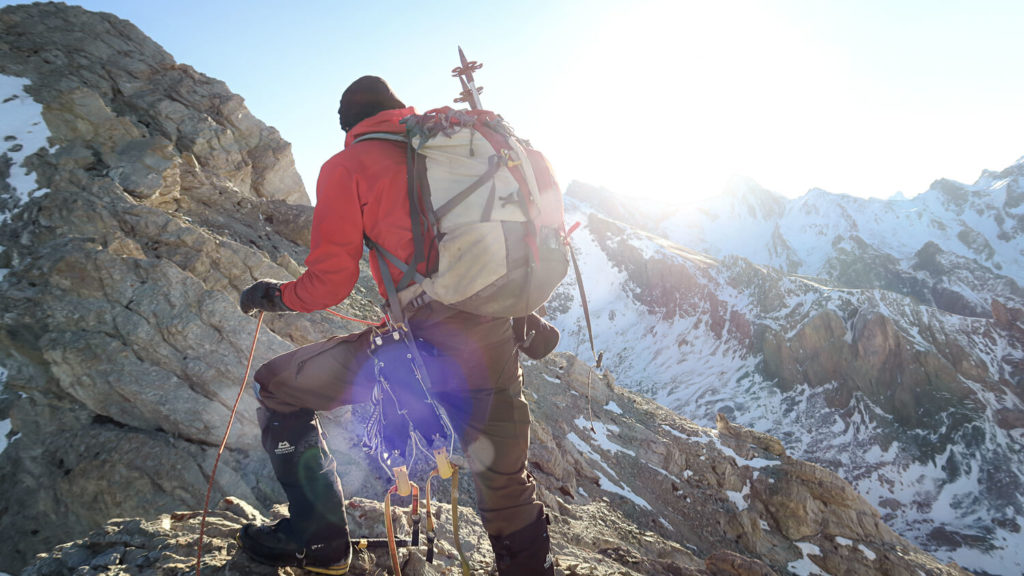 Homme de dos avec sac et matériel d'alpinisme, en montagne