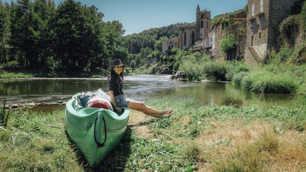 Je suis assise avec mon chapeau sur le canoë devant le village de Lavoûte-Chilhac