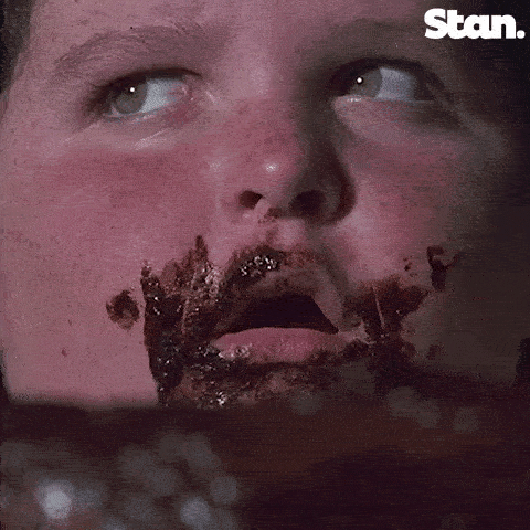 Jeune garçon avec la bouche mâchurée de gâteau au chocolat