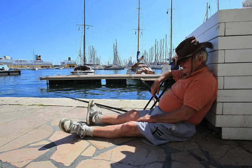 Un homme fait la sieste assis sur la jetée d'un port