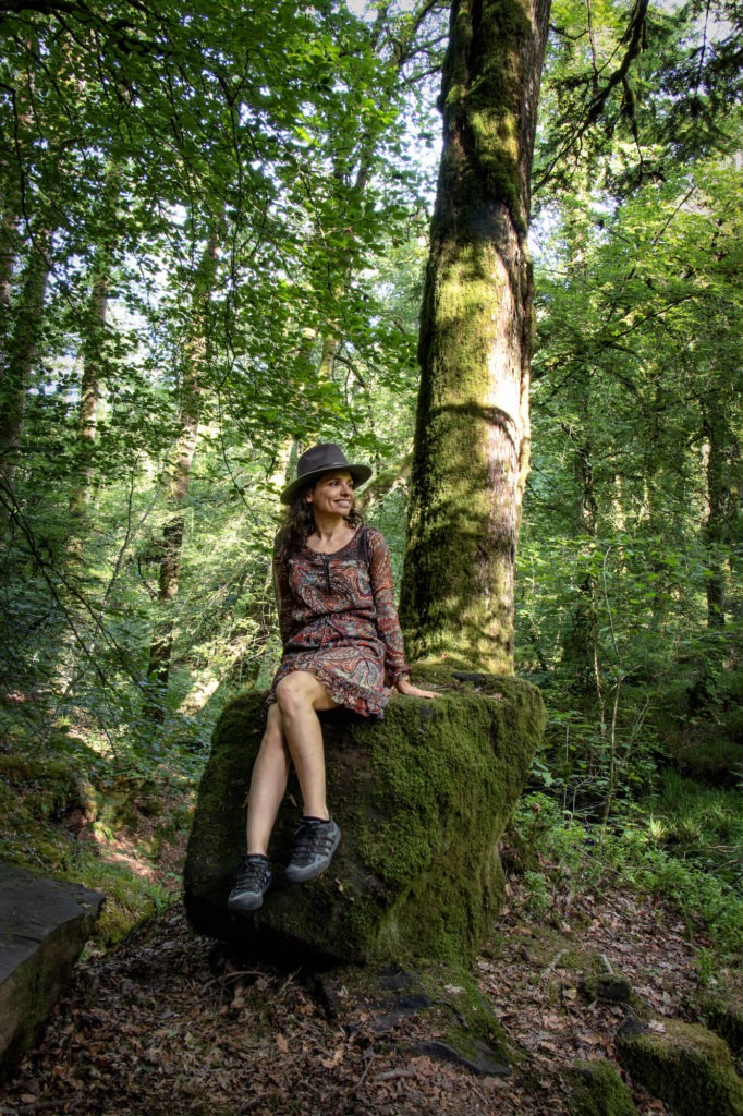 Femme assise sur un rocher au pied d'un arbre