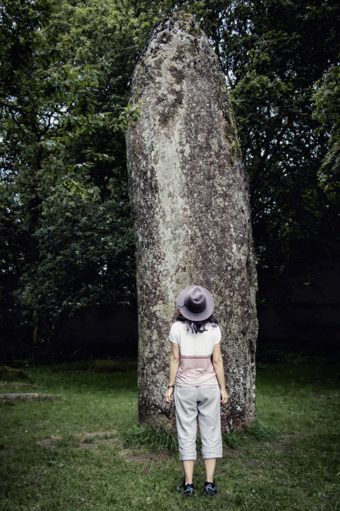 Femme avec chapeau devant de menhir de Kérampeulven