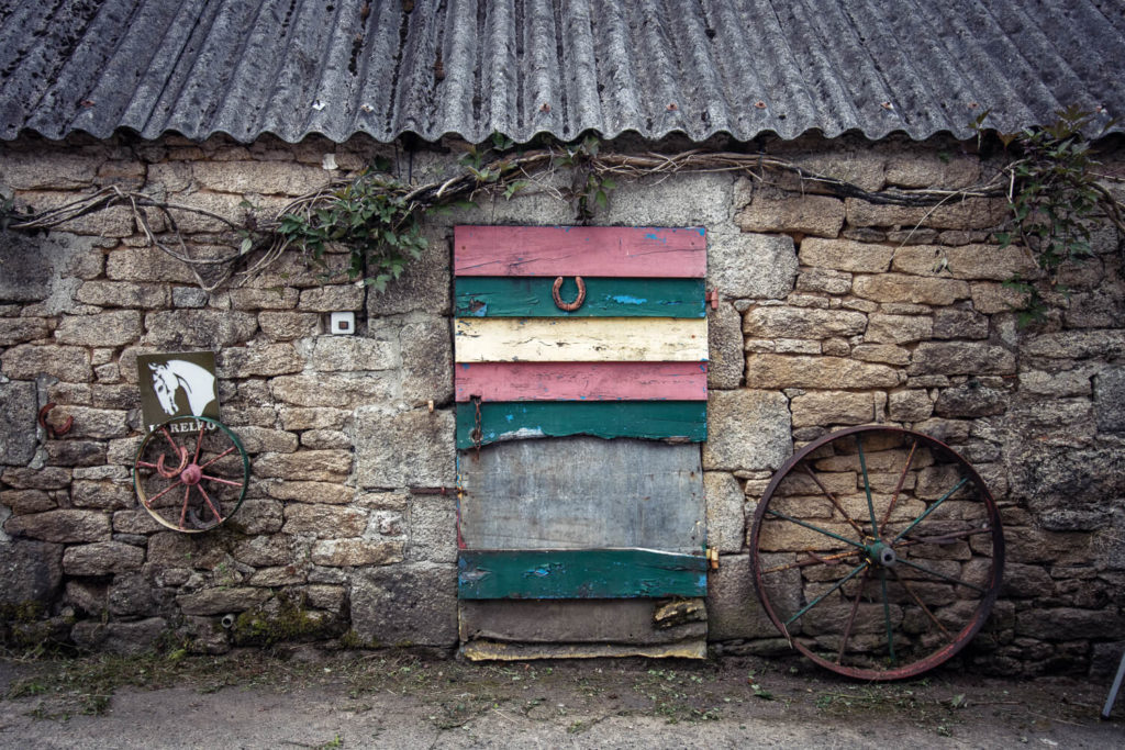 Petite porte ancienne en bois peinte de bandes multicolores, vue lors de mon road-trip en Bretagne dans le hameau de Kérampeulven