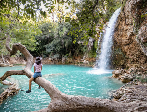 Femme avec chapeau assise sur un tronc d'arbre près de la petite cascade de Sillans