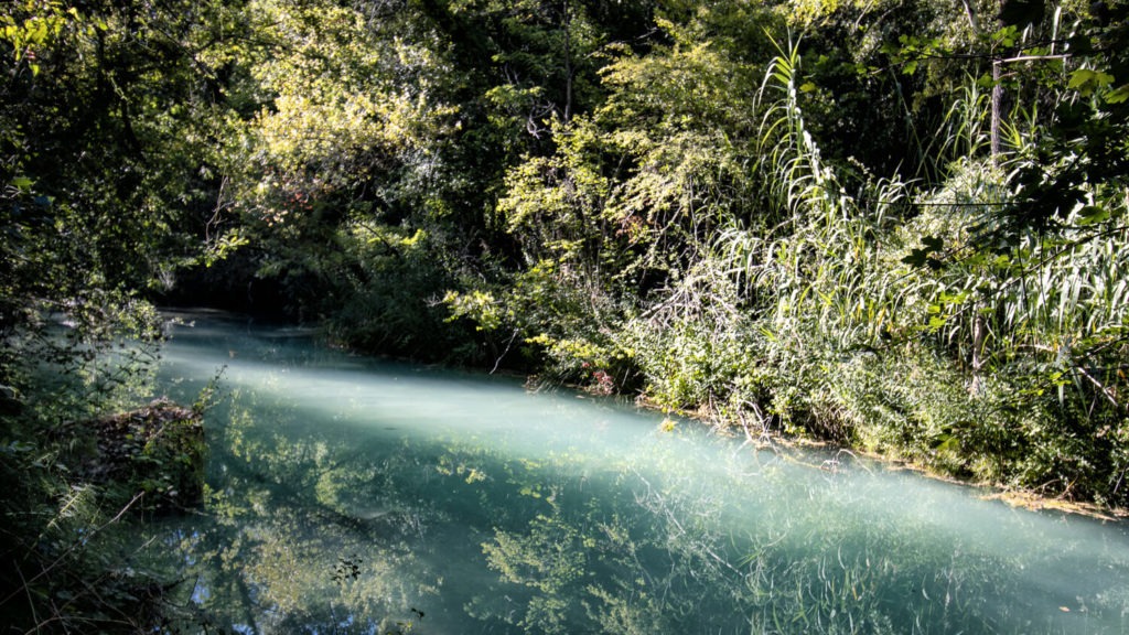 L'eau bleue de la rivière La Besque éclairée d'un rayon de soleil à Sillans-la-cascade