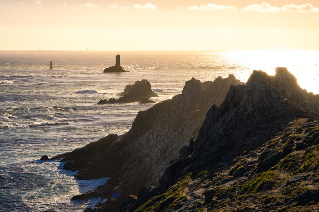 Le phare de La Vieille à la Pointe du Raz, au coucher du soleil devant les rochers de la côte