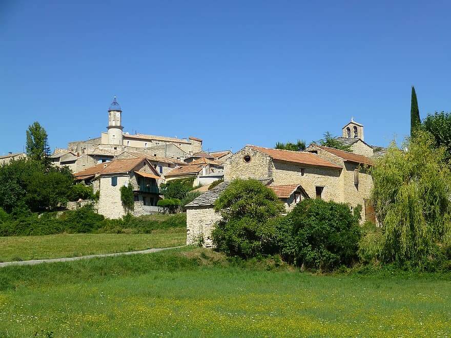 Petit village de provence verte avec maisons en pierre et champs d'herbe au premier plan