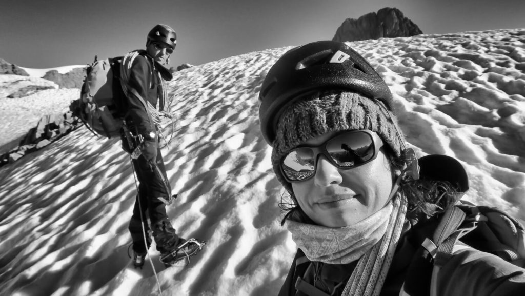 Duo homme et femme en alpinisme, sur une pente de neige avec casques et cordes