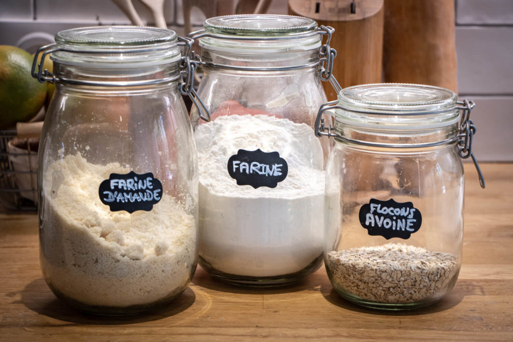 Bocaux de cuisine contenant de la farine, de la poudre d'amande et des flocons d'avoine pour préparation de pancakes vegan