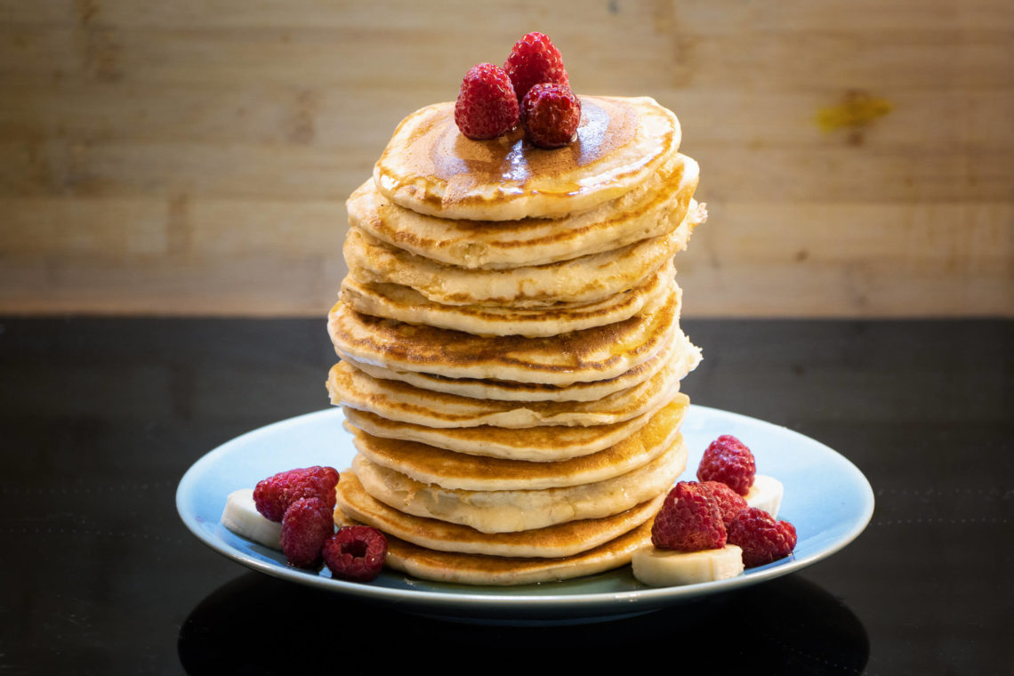 Pile de pancakes vegan avec framboises et bananes, sirop d'érable