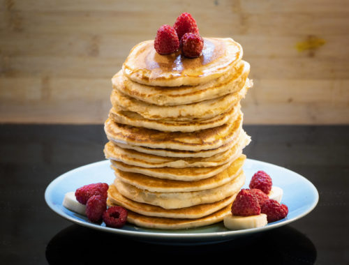 Pile de pancakes vegan avec framboises et bananes, sirop d'érable