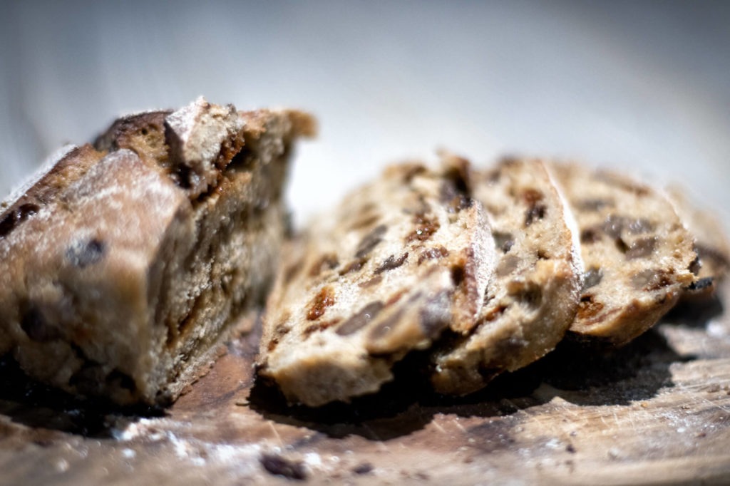 Pain de boulangerie bio aux baies de goji tranché, déposé sur une planche