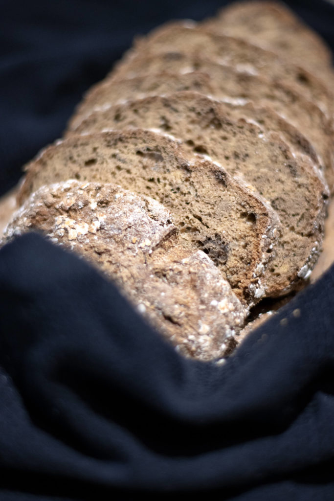 Pain spécial sans gluten découpé en tranches, déposé sur un torchon noir, issu de la boulangerie bio "Au Rythme du Pain" à Montpellier