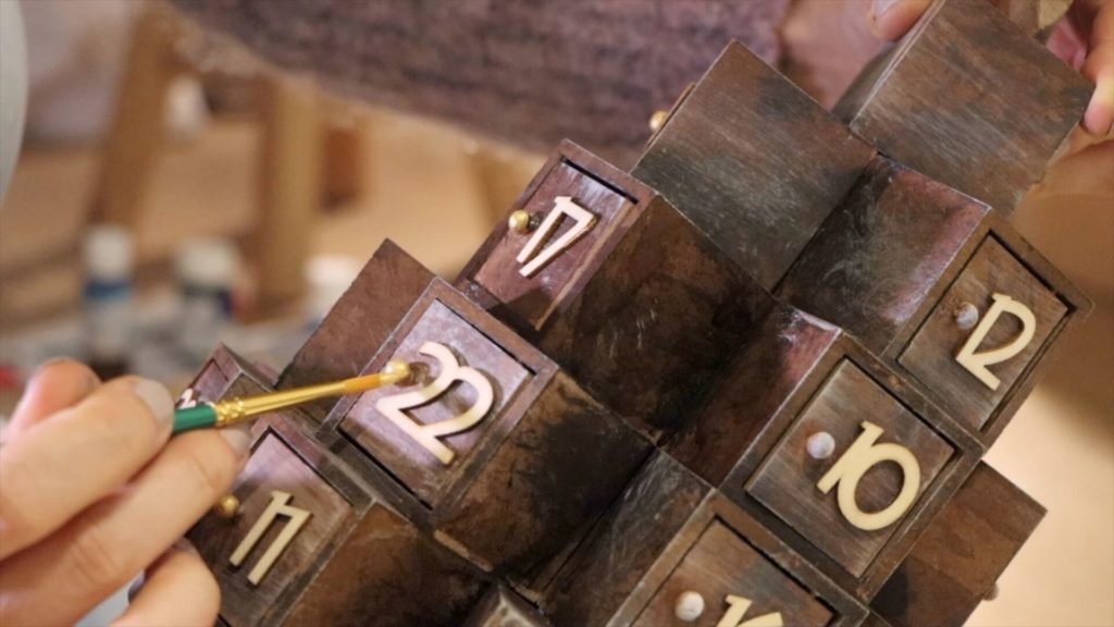 Application de peinture dorée sur les boutons de portes du calendrier de l'avent
